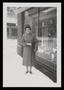 Photograph: [Sheila Emery Allen standing in snow next to storefront window]