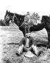 Photograph: [Bethel Baker Sitting with a Saddled Horse]