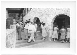 Primary view of object titled '[Church Attendees Gathering for Lunch Under Stone Arches]'.