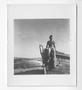 Photograph: [Man Sitting on the Edge of Beached Boat]