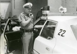 Primary view of object titled '[Arlington Police Officer Bill Taylor speaking over mobile radio, ca. 1965, view 1]'.
