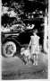 Photograph: [Unidentified girl and dog in front of an automobile]