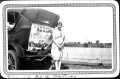 Photograph: [Leta Lucille Hartman standing next to car in front of body of water]