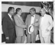 Photograph: [Lamar Fleming, Jr. with shaking hands with unidentified men]
