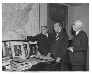 Primary view of object titled '[George A. Hill, Jr. showing a place in Texas on geologic U.S. map to two unidentified men]'.