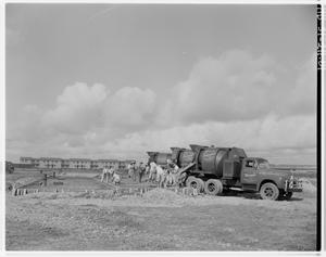 Primary view of object titled '[Trucks and workers pouring foundation outside]'.