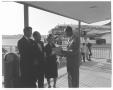 Photograph: [Three men and a woman dressed in formal attire at an airport]