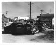 Photograph: [Wrecked cars in front of "Frank's Wrecker Service"]