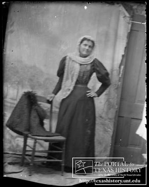 Primary view of object titled '[Woman posed by a chair, a lace shawl draped over her head]'.