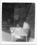 Photograph: [Baby in bassinet in front of Alamo Grocery store]