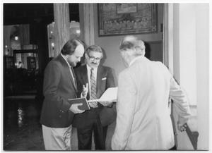 Primary view of object titled '[Tom Kreneck and two men looking at books]'.