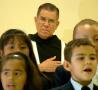 Photograph: [Children sing in front of a Priest]