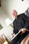 Photograph: [Bishop Kevin Vann sitting on sofa with book]