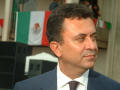 Primary view of [Carlos Garcia de Alba close-up with Mexican flags in background]