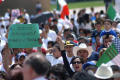 Photograph: [Protesters hold up Mexican and American flags and signs]