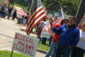 Primary view of [Protesters with large sign and American flag]