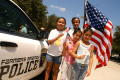 Photograph: [Man with a big U.S. flag and three girls with little U.S. flags stan…