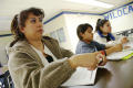 Photograph: [Parent with students listens to presentation at school meeting]