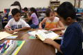 Photograph: [Students share a text book at Crockett Elementary]