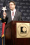 Photograph: [Man speaking at podium with NALEO emblem]