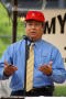Photograph: [Close-up of man in red hat at microphone]