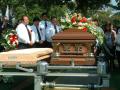 Photograph: [Men standing behind casket at burial site]