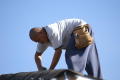 Primary view of [Man bent over and working on roof]