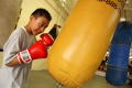 Photograph: [Boy in red boxing gloves hitting yellow heavy bag]