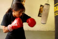 Photograph: [Girl in red boxing gloves punching heavy bag]