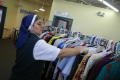 Photograph: [Nun arranges clothing on a rack]