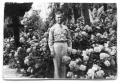 Photograph: [Buddy Sinclair in uniform by flower bush]