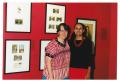 Photograph: [Two Women Standing in Front of a Red Gallery Wall]