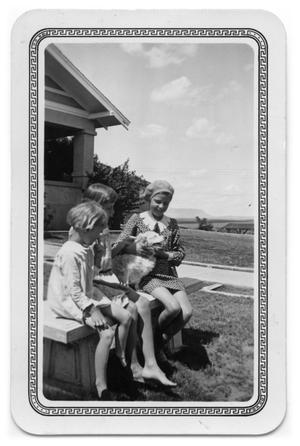 Primary view of object titled 'Girls sitting on a bench with a dog'.