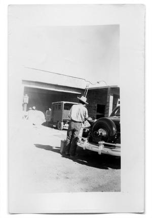 Primary view of object titled 'Man standing next to a car'.