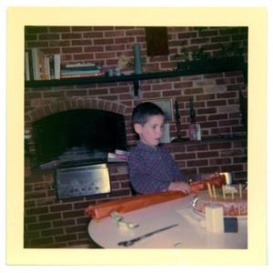 Primary view of object titled 'Boy at a table with a wrapped package'.