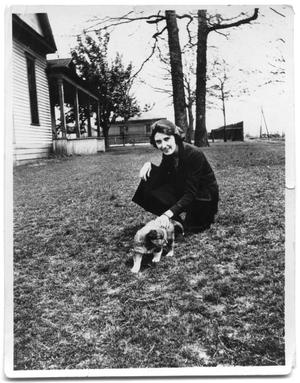 Primary view of object titled 'Nancy Della Cruse kneeling next to a puppy'.