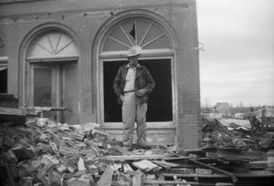 Primary view of object titled '[Photograph of Man Standing on Debris]'.