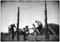 Primary view of Men Climbing Over a Fence