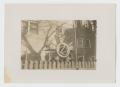 Photograph: [Wheel in Front of Building]