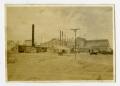 Photograph: [Frisco Boxcars by Acme Cement Plaster Buildings]