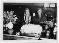 Photograph: [Otto Lindig and His Wife Sitting at a Table with a Cake]
