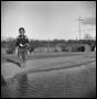 Photograph: [Child By a Dirt Road and a Watery Ditch]
