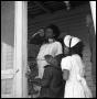 Photograph: [Woman Standing in a Porch Doorway with Children]