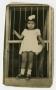 Postcard: [Photograph of Little Girl Standing by Window]