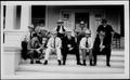 Primary view of [Ten men wearing hats and sitting on the porch of a white wooden house]