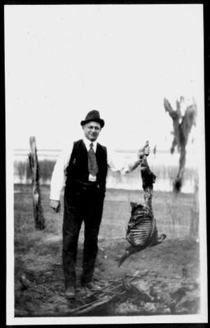 Primary view of object titled '[A man holding up a large portion of barbecued meat at the George Camp]'.