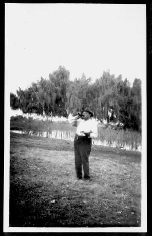 Primary view of object titled '[A man drinking a bottled beverage at Camp George]'.