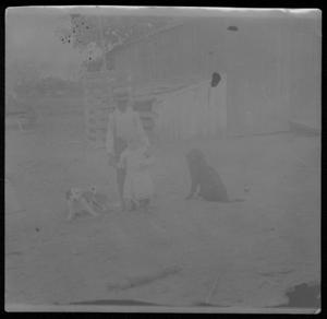 Primary view of object titled '[A boy standing behind a child in the yard of the J.H.P. Davis house]'.