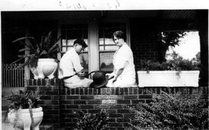 Primary view of object titled '["Aline & Len" sitting on the ledge of a brick porch]'.