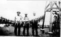 Photograph: [A.P. George and three men standing behind a string of fish]